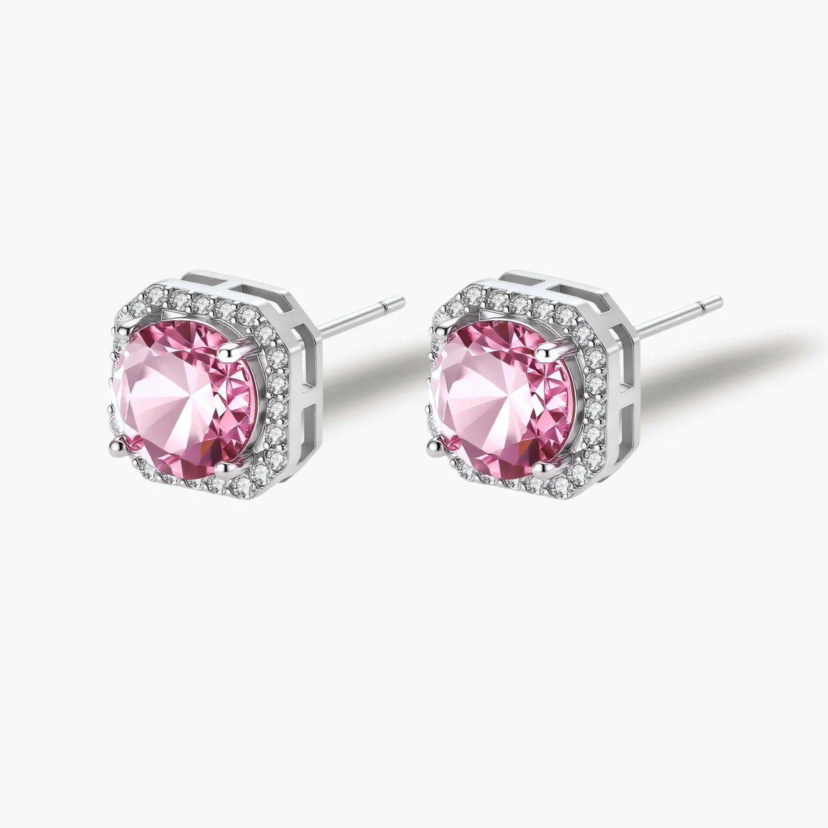 Pink moissanite studs in octagonal sterling silver halo settings with sparkling accent stones on cream background.