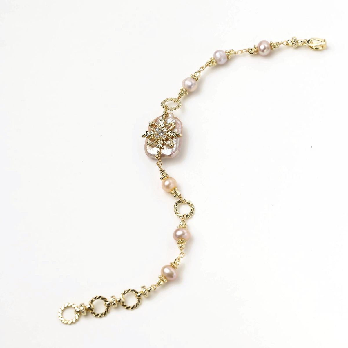 Gold-plated bracelet with pink baroque pearl centerpiece, floral connector, and freshwater pearls