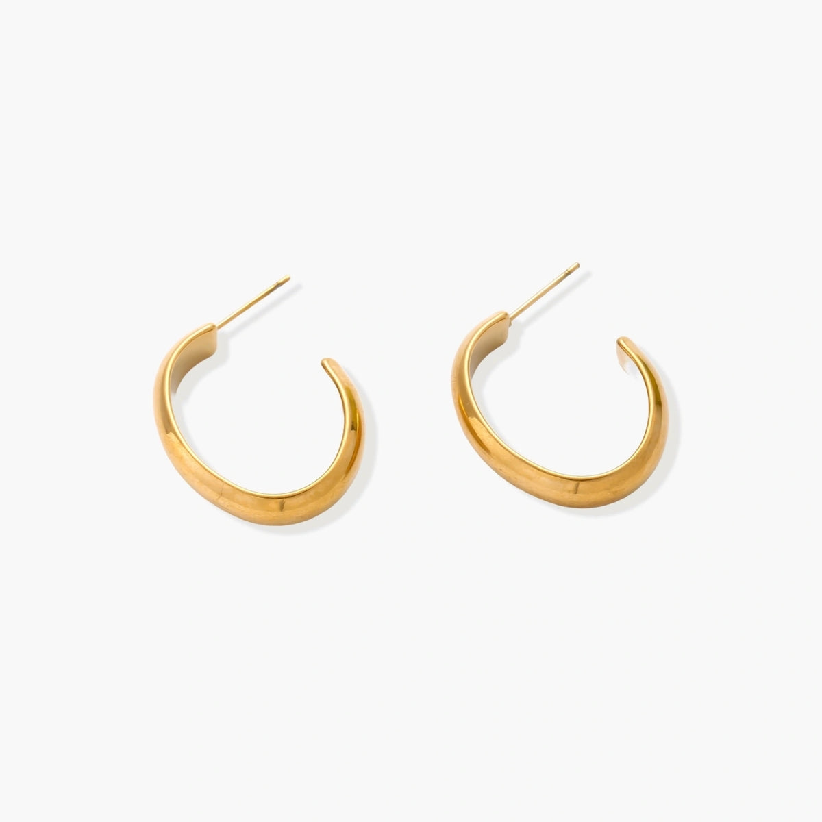 Chunky tubular hoop earrings in warm 14K gold-plated finish with smooth polished surface on cream background.